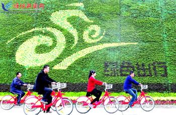 市民騎公共自行車路過市人民廣場一處花壇。記者 張馳